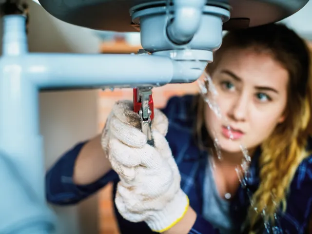 Female lpumber repairing a sink leak
