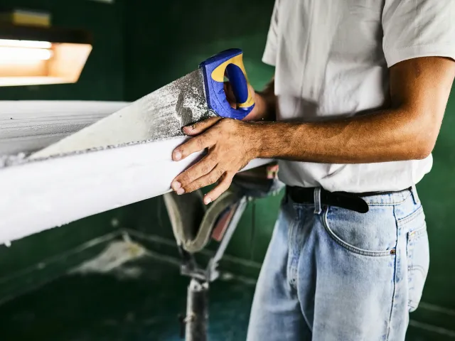 A man cuts a board with a handheld saw