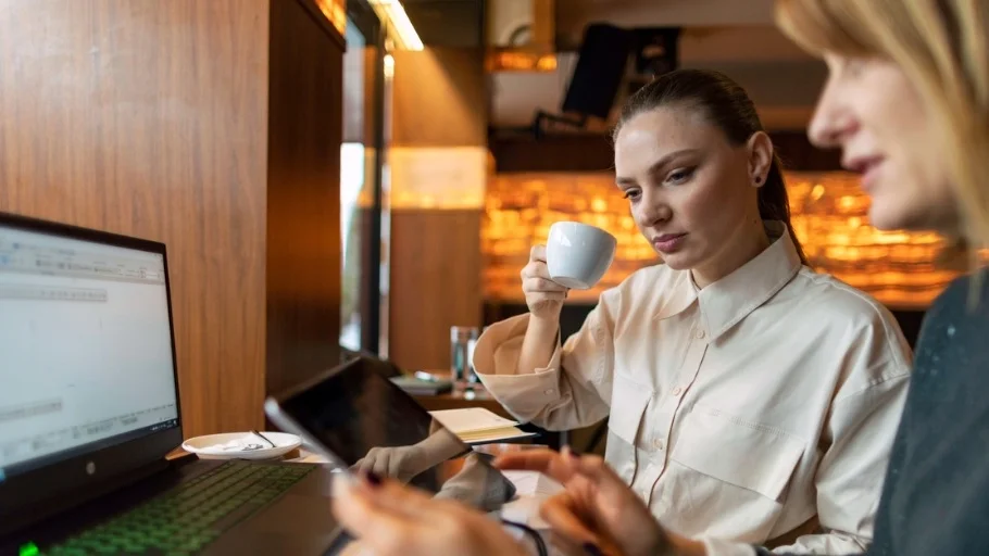 Two women reviewing expenses on a cell phone and paperwork
