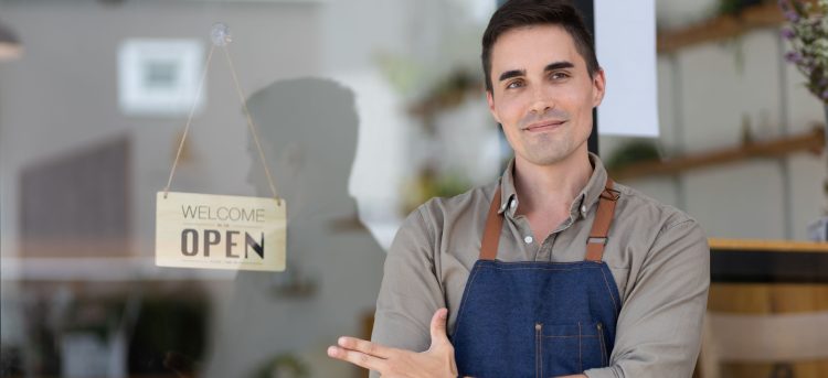 Entrepreneur or successful small business owner standing in his modern coffee roastrery at doorway store. Waitress waiting for clients at coffee shop.