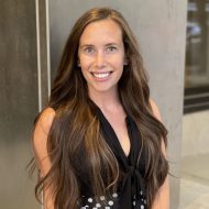 Photo of Amanda Triest, PR Manager for Nav. She has long brown hair and is wearing a black and white dress and smiling at the camera.